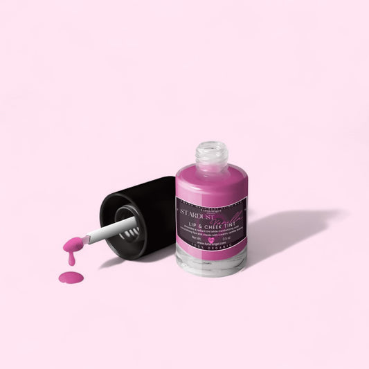 Pink lip and cheek tint bottle with applicator on a light pink background